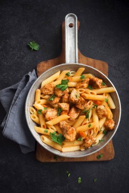 Domates soslu tavuk, maydanoz tavada penne makarna. Tavuk İtalyan penne makarna kopya alanı, Italyan Mutfagi ile siyah arka plan üzerinde.