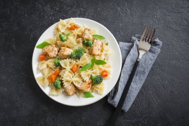 Farfalle makarna Tavuk ve sebze ile. Siyah arka plan, kopya alanı üzerine makarna salatası.