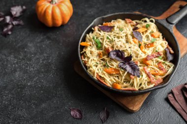 Kabak ve dökme demir tavada pastırma ile sonbahar makarna. Ev yapımı spagetti kabak pasta pastırma, parmesan peyniri ve fesleğen siyah, kopya alanı ile. Sonbahar gıda.