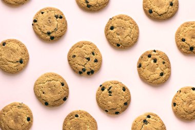 Çikolatalı kurabiye pembe pastel arka planda, üstten görünüm.