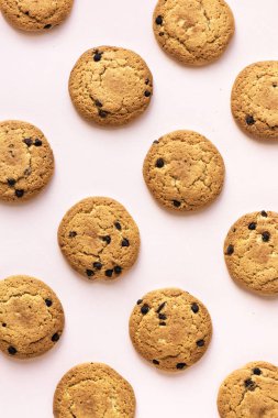 Çikolatalı kurabiye pembe pastel arka planda, üstten görünüm.