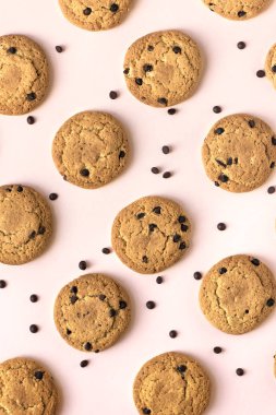 Çikolatalı kurabiye pembe pastel arka planda, üstten görünüm.