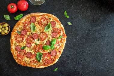 İtalyan Pizza domates, salam, yeşil zeytin, peynir ve fesleğen yaprakları, ana sayfa görünümü siyah. Taze ev yapımı Pizza, kopya alanı.