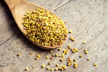 Arı polen içinde kaşık ahşap arka plan üzerinde. Sağlıklı organik ham diyet vejetaryen gıda içerikler - arı polen.