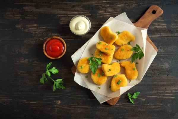 Tavuk nuggets ve koyu ahşap zemin, kopya alanı üzerine sos. Fried nuggets ketçap ve mayonez ile.