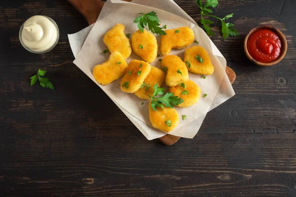 Tavuk nuggets ve koyu ahşap zemin, kopya alanı üzerine sos. Fried nuggets ketçap ve mayonez ile.