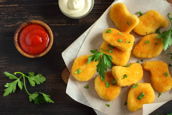 Tavuk nuggets ve koyu ahşap zemin, kopya alanı üzerine sos. Fried nuggets ketçap ve mayonez ile.