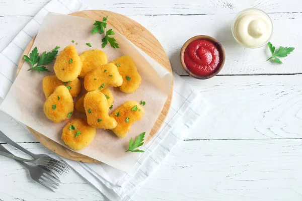 Tavuk nuggets ve beyaz ahşap zemin, kopya alanı üzerine sos. Fried nuggets ketçap ve mayonez ile.