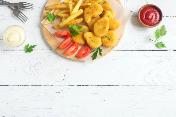 Tavuk nuggets, kızarmış patates ve beyaz ahşap zemin, üzerine sosu alanı kopyalayın. Fried nuggets ve ketçap ve mayonez ile patates.