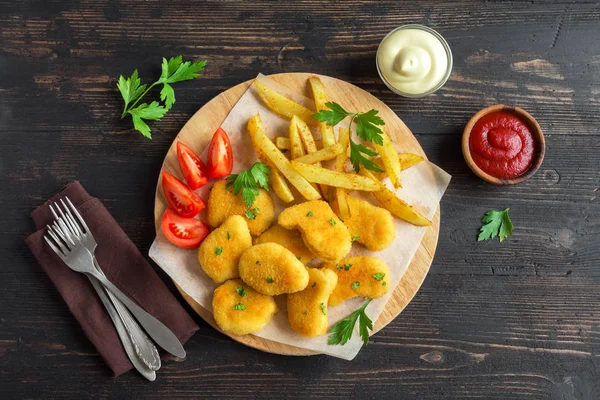Tavuk nuggets, patates kızartması ve koyu ahşap arka plan, sosu alanı kopyalayın. Fried nuggets ve ketçap ve mayonez ile patates.