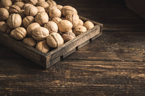 Organic Walnuts in rustic wooden box, top view, copy space. Seasonal harvest of walnuts.