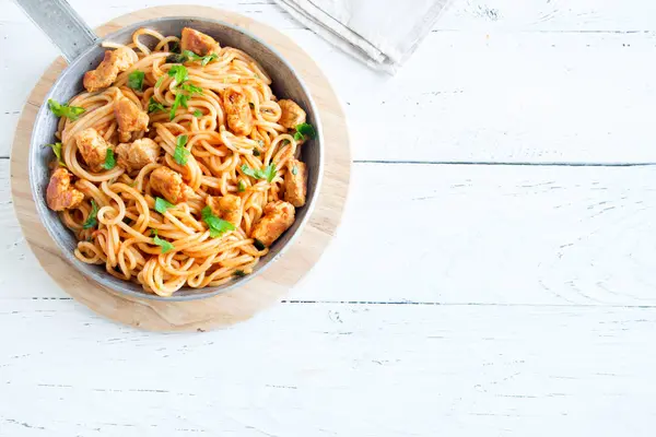 Domates soslu tavuk, maydanoz tavada spagetti makarna. Tavuk spagetti makarna kopya alanı, Italyan Mutfagi ile beyaz ahşap zemin üzerinde.