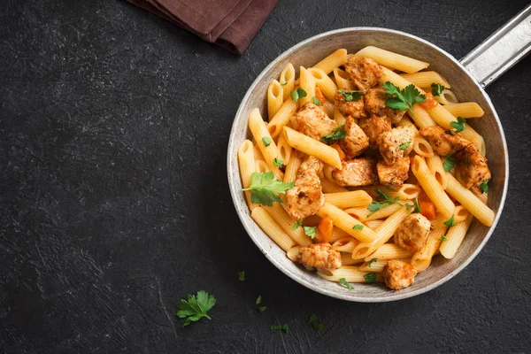 Domates soslu tavuk, maydanoz tavada penne makarna. Tavuk İtalyan penne makarna kopya alanı, Italyan Mutfagi ile siyah arka plan üzerinde.