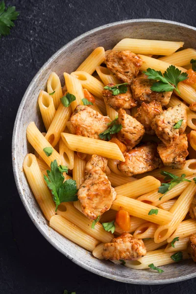 Domates soslu tavuk, maydanoz tavada penne makarna. Tavuk İtalyan penne makarna kopya alanı, Italyan Mutfagi ile siyah arka plan üzerinde.