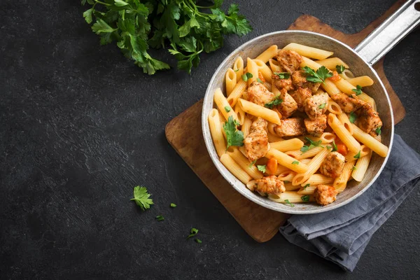 Domates soslu tavuk, maydanoz tavada penne makarna. Tavuk İtalyan penne makarna kopya alanı, Italyan Mutfagi ile siyah arka plan üzerinde.