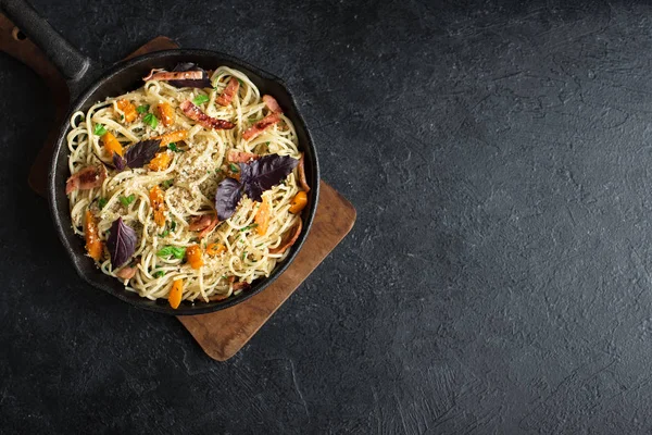 Kabak ve dökme demir tavada pastırma ile sonbahar makarna. Ev yapımı spagetti kabak pasta pastırma, parmesan peyniri ve fesleğen siyah, kopya alanı ile. Sonbahar gıda.