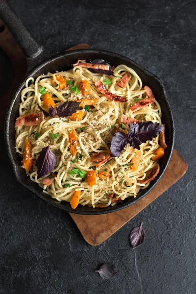 Kabak ve dökme demir tavada pastırma ile sonbahar makarna. Ev yapımı spagetti kabak pasta pastırma, parmesan peyniri ve fesleğen siyah, kopya alanı ile. Sonbahar gıda.