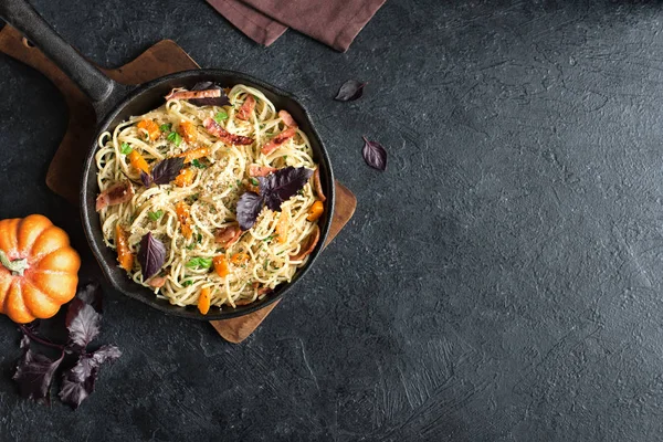 Kabak ve dökme demir tavada pastırma ile sonbahar makarna. Ev yapımı spagetti kabak pasta pastırma, parmesan peyniri ve fesleğen siyah, kopya alanı ile. Sonbahar gıda.
