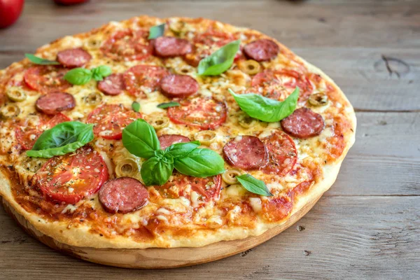 İtalyan Pizza domates, salam, yeşil zeytin, peynir ve fesleğen ile tahta masada bırakır. Taze ev yapımı Pizza, kopya alanı.