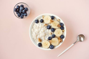 Ceviz, yaban mersini ve muz kase pembe üzerinde-sağlıklı organik kahvaltı, meyve, bal ve fındık ile yulaf yulaf lapası