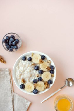 Ceviz, yaban mersini ve muz kase üzerinde pastel pembe - sağlıklı organik kahvaltı, meyve, bal ve fındık ile yulaf yulaf lapası