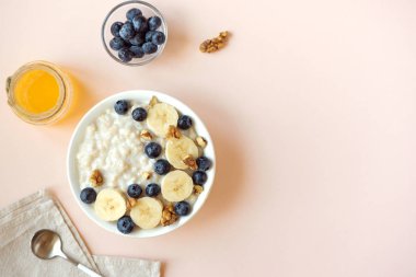 Ceviz, yaban mersini ve muz kase üzerinde pastel pembe - sağlıklı organik kahvaltı, meyve, bal ve fındık ile yulaf yulaf lapası