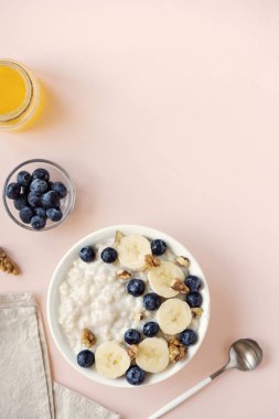 Ceviz, yaban mersini ve muz kase pembe üzerinde-sağlıklı organik kahvaltı, meyve, bal ve fındık ile yulaf yulaf lapası