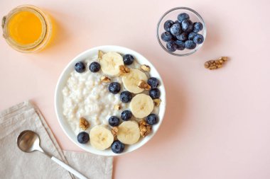 Ceviz, yaban mersini ve muz kase üzerinde pastel pembe - sağlıklı organik kahvaltı, meyve, bal ve fındık ile yulaf yulaf lapası