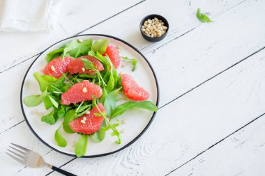 Roka, greyfurt ve çam fıstığı ahşap üzerinde kopya alanı Taze narenciye salatası. Çiğ vegan vejetaryen bahar detoks salata, sağlıklı gıda.