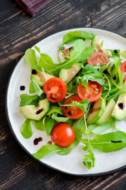 Roka ve ahşap üzerine balsamik sirke, kopya alanı ile avokado ve domates salatası. Sağlıklı beslenme vegan vejetaryen yaz sebze salatası gıda kavramı.