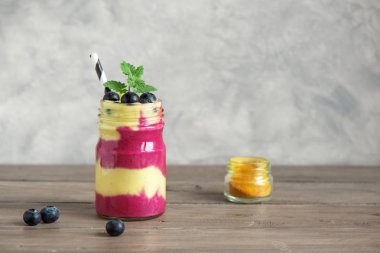 Yaban mersini ve zerdeçal güler yüzlü sağlıklı kahvaltı için. Karanlık beton zemin, kopya alanı üzerine çilek ile renkli katmanlı güler yüzlü.