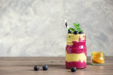 Yaban mersini ve zerdeçal güler yüzlü sağlıklı kahvaltı için. Karanlık beton zemin, kopya alanı üzerine çilek ile renkli katmanlı güler yüzlü.