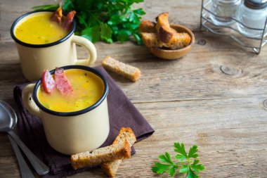 Bezelye çorbası ile jambon füme ve ahşap arka plan üzerinde kruton bölün. Kupalar kış öğle yemeği için sağlıklı ev yapımı kalın split çorba.