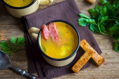 Bezelye çorbası ile jambon füme ve ahşap arka plan üzerinde kruton bölün. Kupalar kış öğle yemeği için sağlıklı ev yapımı kalın split çorba.