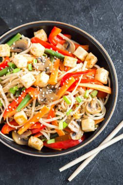 Udon erişte, soya peyniri, mantar ve sebze Fry karıştırın. Asya vegan vejetaryen yemek, yemek, wok siyah arka plan, kopya alanı üzerinde heyecan kızartma.