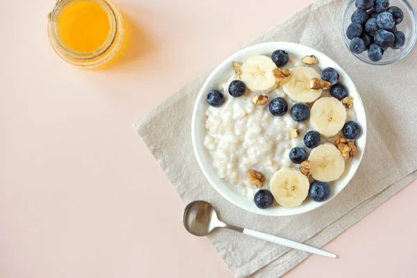 Ceviz, yaban mersini ve muz kase üzerinde pastel pembe - sağlıklı organik kahvaltı, meyve, bal ve fındık ile yulaf yulaf lapası