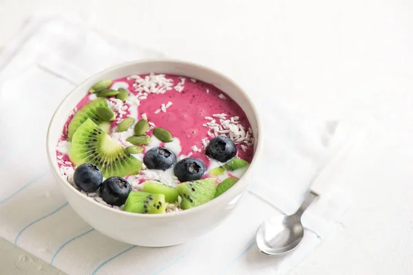Smoothie bowl with fresh berries, fruits, seeds and coconut cream for healthy vegan vegetarian diet breakfast. Acai blueberry coconut smoothie bowl.