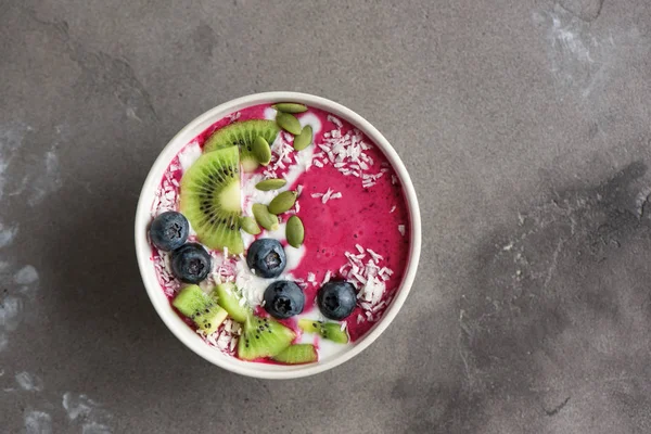 Smoothie bowl with fresh berries, fruits, seeds and coconut cream for healthy vegan vegetarian diet breakfast. Acai blueberry coconut smoothie bowl.