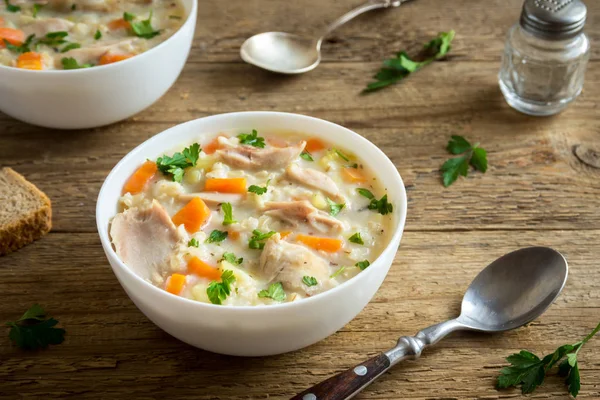 Chicken and Wild Rice Soup. Homemade fresh creamy soup with chicken, vegetables and wild rice in white bowl close up.