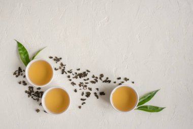 Seramik bardak, Kuru yeşil oolong çay ve çay yaprakları üstten görünüm, beyaz taş masada yeşil çay kopyalama alanı.