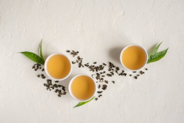 Seramik bardak, Kuru yeşil oolong çay ve çay yaprakları üstten görünüm, beyaz taş masada yeşil çay kopyalama alanı.