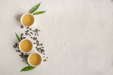 Seramik bardak, Kuru yeşil oolong çay ve çay yaprakları üstten görünüm, beyaz taş masada yeşil çay kopyalama alanı.