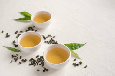 Seramik bardak, Kuru yeşil oolong çay ve çay yaprakları kopya alanı beyaz taş masada yeşil çay.