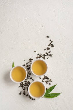 Seramik bardak, Kuru yeşil oolong çay ve çay yaprakları üstten görünüm, beyaz taş masada yeşil çay kopyalama alanı.