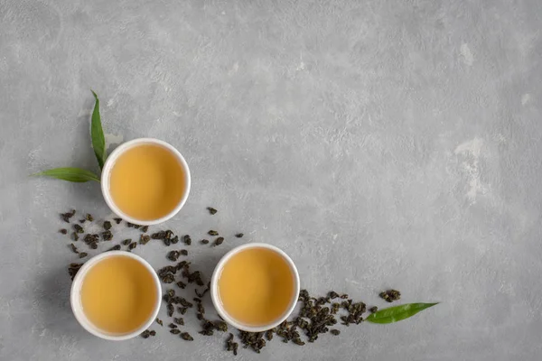 セラミック カップ 乾燥緑のウーロン茶と灰色の石のテーブル トップ ビューで茶葉の緑茶をコピー スペース — ストック写真