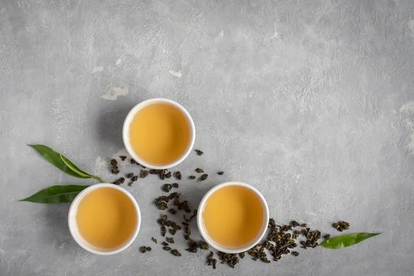 セラミック カップ 乾燥緑のウーロン茶と灰色の石のテーブル トップ ビューで茶葉の緑茶をコピー スペース — ストック写真
