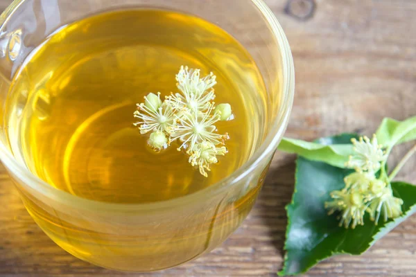 Demet taze ıhlamur çiçek ahşap arka plan üzerinde çay sağlıklı Bitkisel linden. Organik linden çay, bitkisel içki.