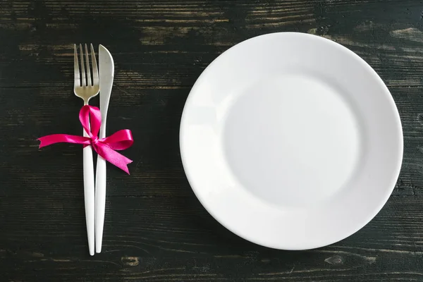 浪漫的餐桌设置与白色板 现代餐具和红丝带在黑色的木质背景 顶部视图 复制空间 浪漫晚餐 婚礼理念 — 图库照片