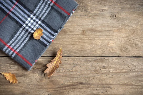 Sonbahar. Ahşap arka plan üzerinde kuru yaprakları ile gri kareli ekose.