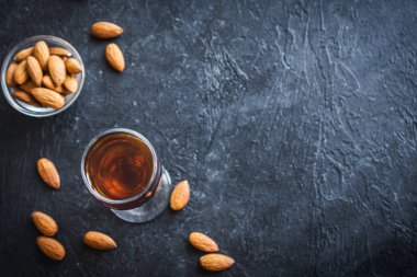 İtalyan likörü Amaretto badem siyah taş arka planda, kopya alanı ile